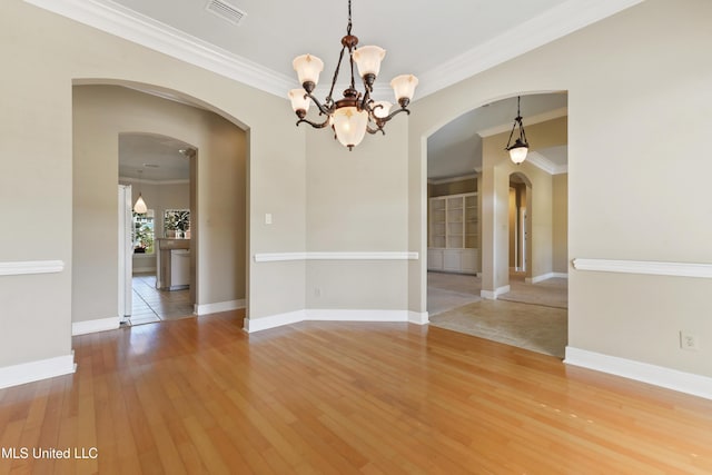 426 Carmargue Ln, Biloxi, MS 39531 - unfurnished room with crown molding, wood finished floors, a chandelier, arched walkways, and baseboards