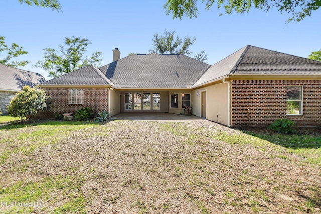 426 Carmargue Ln, Biloxi, MS 39531 - rear view of house with a chimney, a shingled roof, a patio area, brick siding, and a lawn