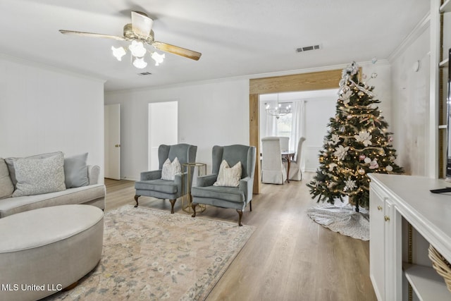 living room featuring crown molding, ceiling fan with notable chandelier, and light hardwood / wood-style floors