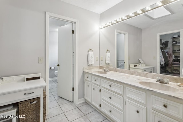 bathroom with a skylight, tile patterned flooring, vanity, and toilet