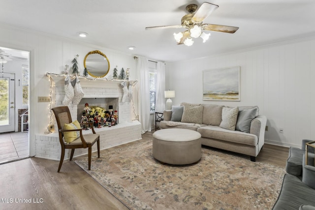 living room with ceiling fan, ornamental molding, hardwood / wood-style floors, and a fireplace