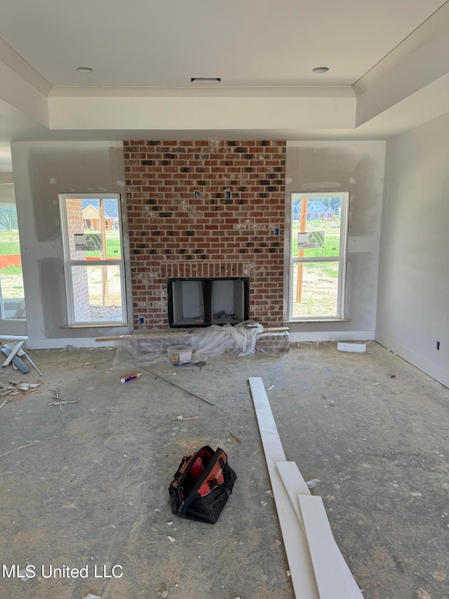 unfurnished living room featuring crown molding, a fireplace, and a tray ceiling