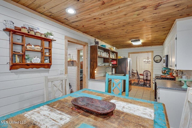 dining space featuring an inviting chandelier, wood ceiling, and wood walls