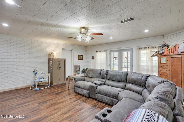 living room featuring brick wall, dark wood-type flooring, and ceiling fan