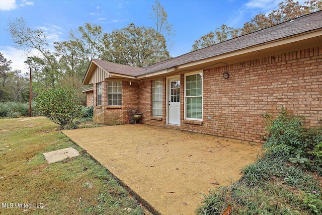 entrance to property featuring a patio and a lawn