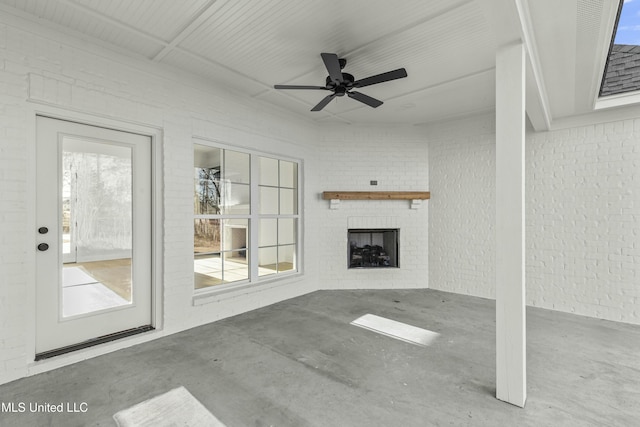 unfurnished living room with brick wall, concrete floors, and ceiling fan