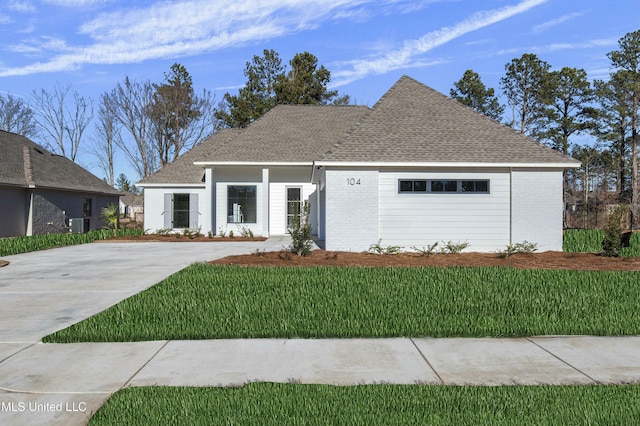 view of front of house featuring a garage, a front yard, and central air condition unit