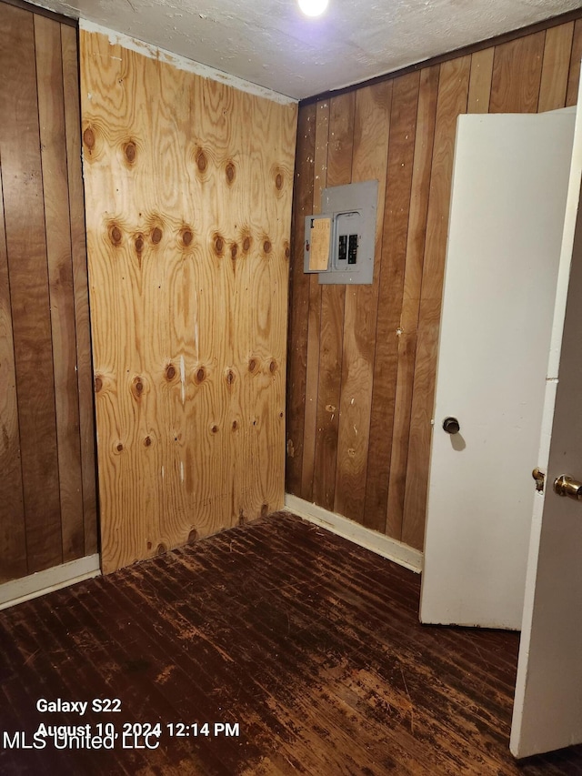 spare room featuring wood walls, electric panel, and dark hardwood / wood-style flooring