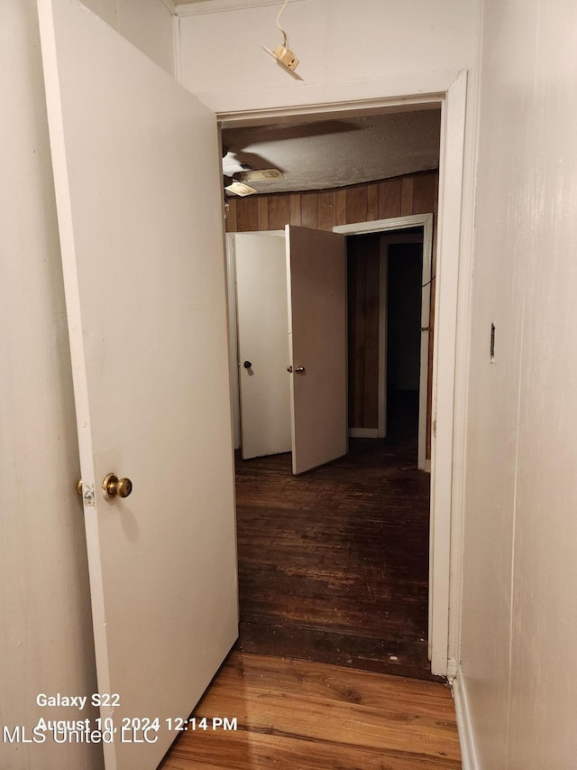 hallway featuring dark hardwood / wood-style floors and wood walls