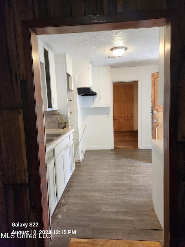 hall with light hardwood / wood-style floors, a textured ceiling, and sink