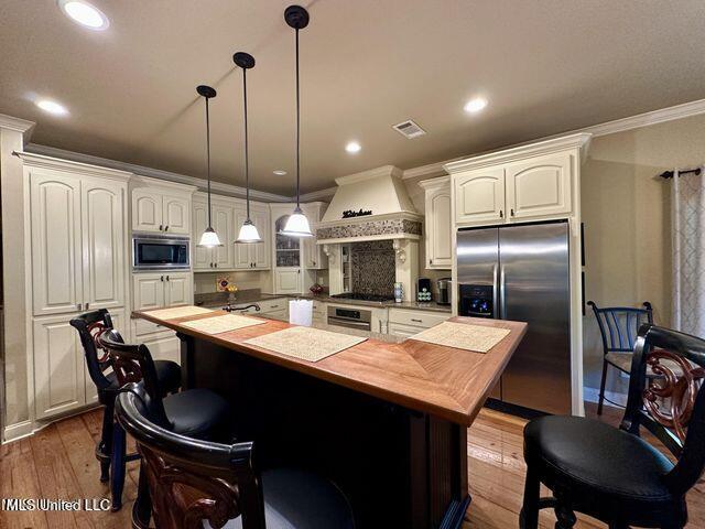 139 Glen Auburn Dr, Clinton, MS 39056 - kitchen with stainless steel appliances, custom range hood, butcher block countertops, a kitchen island, and crown molding