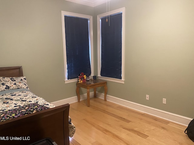 bedroom with baseboards, ornamental molding, and light wood-type flooring