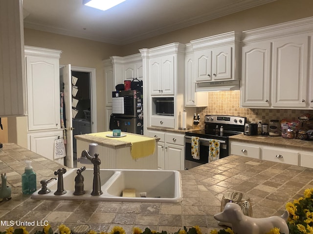 kitchen with under cabinet range hood, white cabinets, tile counters, tasteful backsplash, and appliances with stainless steel finishes