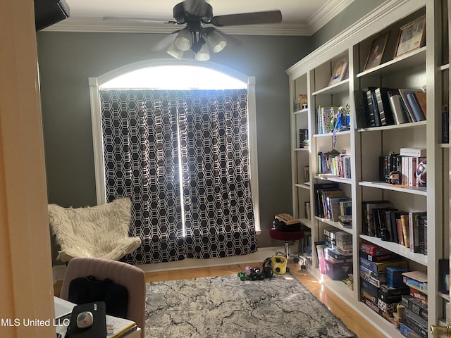 sitting room with wood finished floors, a ceiling fan, and ornamental molding