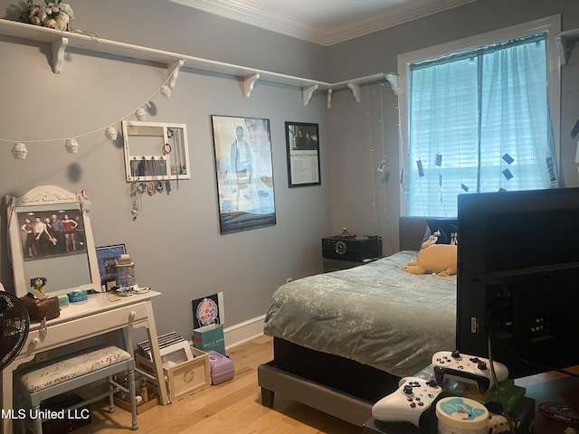 bedroom with baseboards, ornamental molding, and wood finished floors