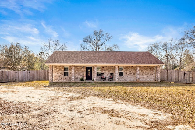 ranch-style home featuring a shingled roof, fence, and brick siding