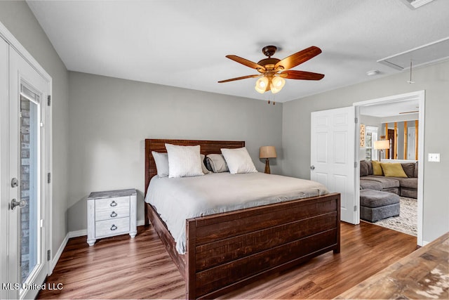 bedroom with attic access, ceiling fan, baseboards, and wood finished floors