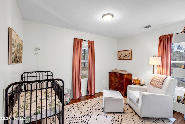 bedroom featuring light wood finished floors, multiple windows, and visible vents