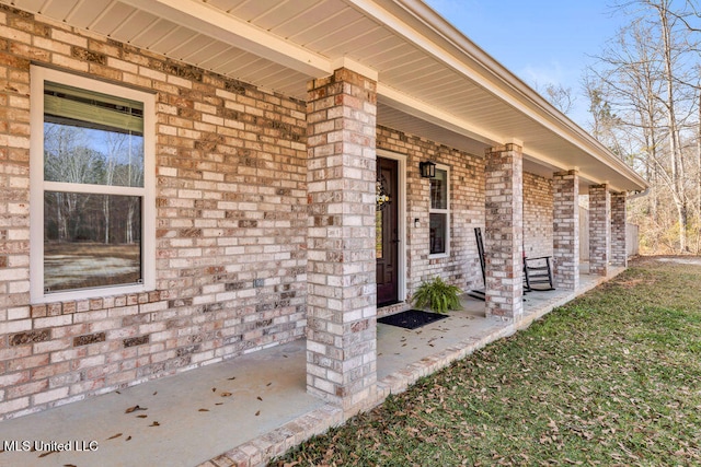 view of exterior entry with covered porch and brick siding