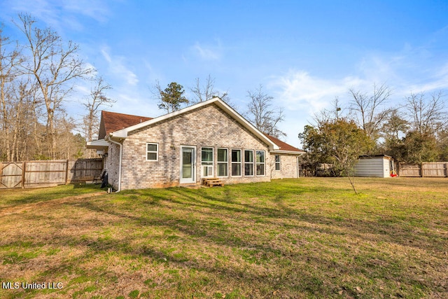 back of house with a lawn, a fenced backyard, an outbuilding, a shed, and brick siding