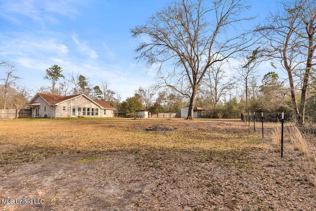 view of yard with an outbuilding, a storage unit, and fence