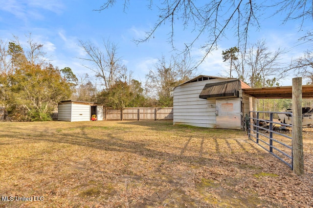 view of yard featuring a shed, fence, and an outbuilding