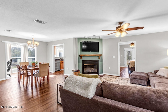 living area featuring dark wood-style floors, a glass covered fireplace, and visible vents