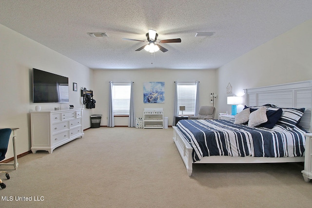 bedroom with ceiling fan, light carpet, and a textured ceiling