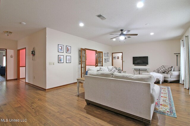 living room featuring a textured ceiling, dark hardwood / wood-style floors, and ceiling fan