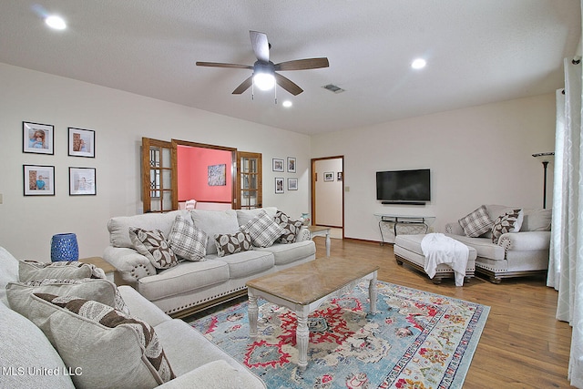 living room with hardwood / wood-style floors, a textured ceiling, and ceiling fan