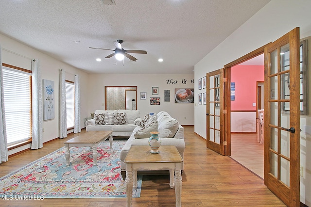 living room with french doors, a textured ceiling, light wood-type flooring, and ceiling fan