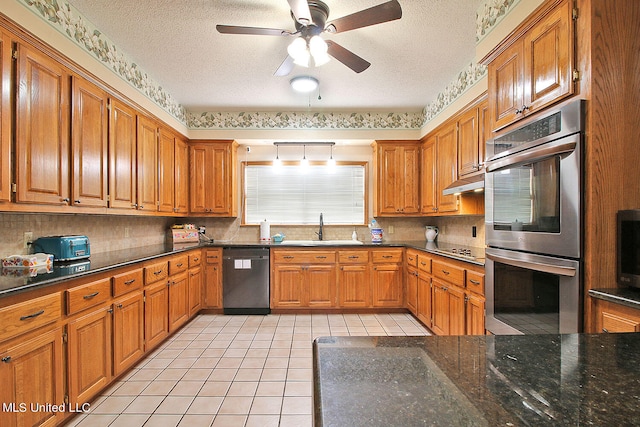 kitchen featuring stainless steel appliances, sink, light tile patterned flooring, a textured ceiling, and ceiling fan