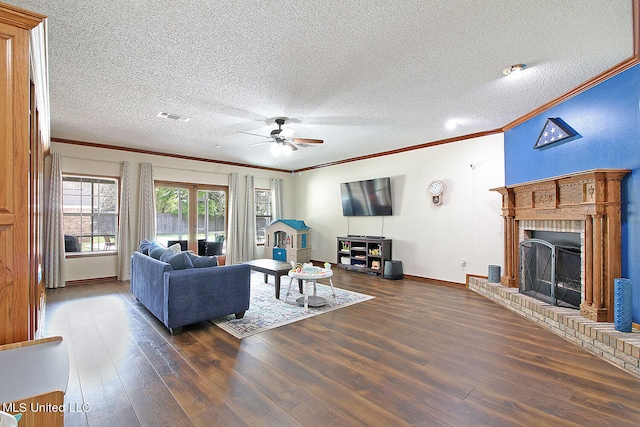 living room featuring dark wood-type flooring, crown molding, a textured ceiling, a fireplace, and ceiling fan