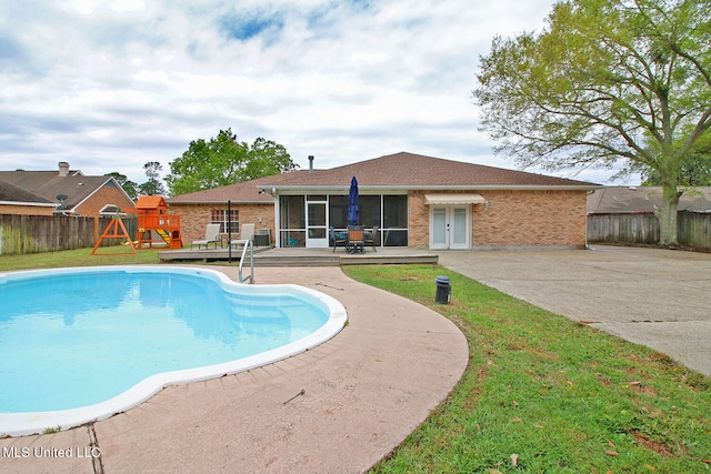 view of pool featuring a patio, a playground, and a sunroom