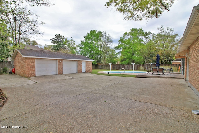 exterior space with a fenced in pool, a patio, and a garage