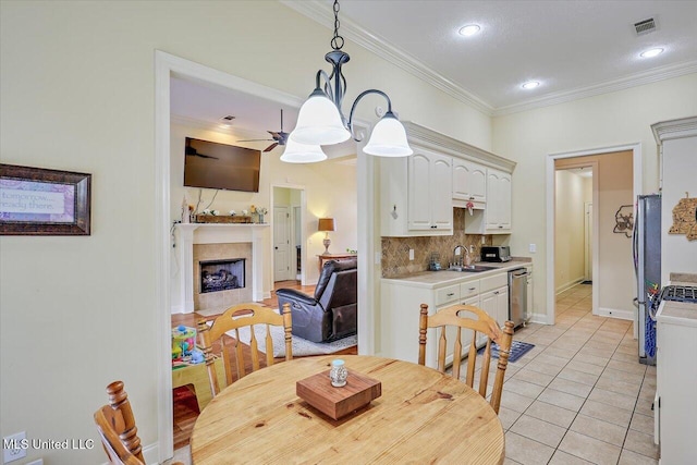 dining room featuring light tile patterned floors, a premium fireplace, baseboards, visible vents, and crown molding