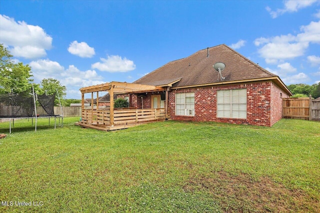back of property featuring a wooden deck, a trampoline, a fenced backyard, and brick siding