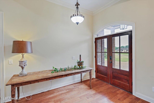 foyer featuring wood finished floors, french doors, crown molding, and baseboards