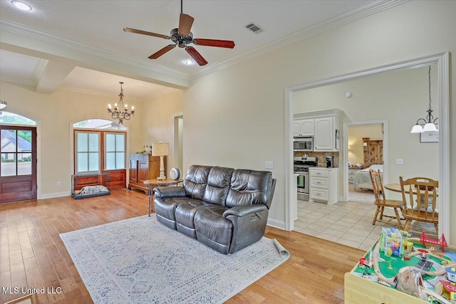 living area with ornamental molding, light wood-type flooring, visible vents, and ceiling fan with notable chandelier