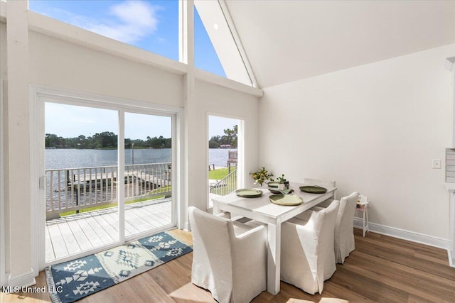 dining area with wood-type flooring, high vaulted ceiling, and a water view