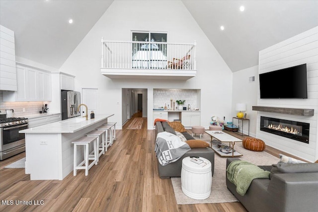 living room with high vaulted ceiling and light hardwood / wood-style floors