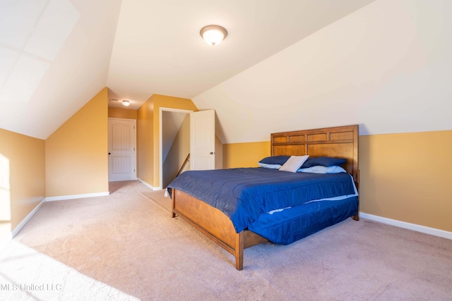 bedroom with baseboards, vaulted ceiling, and light carpet