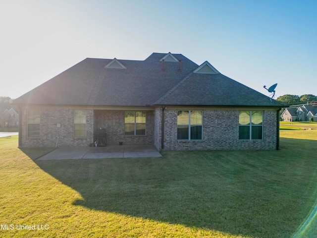 back of house with a patio, a yard, a shingled roof, and brick siding