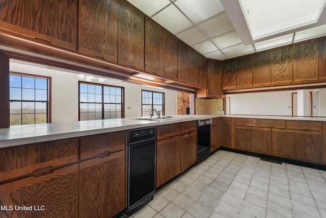 kitchen with dark brown cabinetry, kitchen peninsula, and black dishwasher