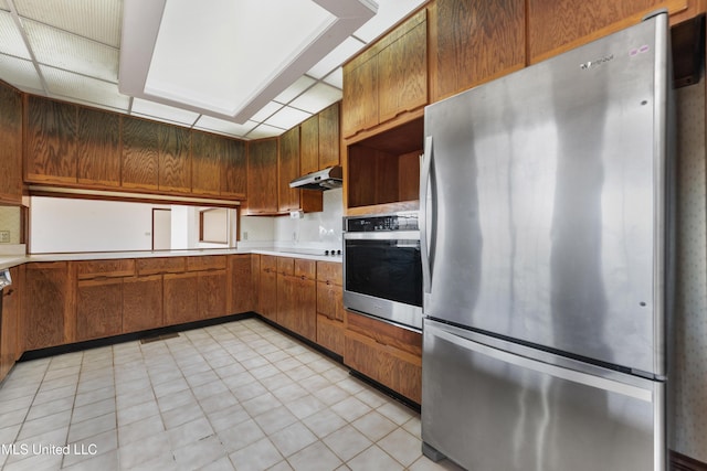 kitchen with appliances with stainless steel finishes, backsplash, and light tile patterned floors