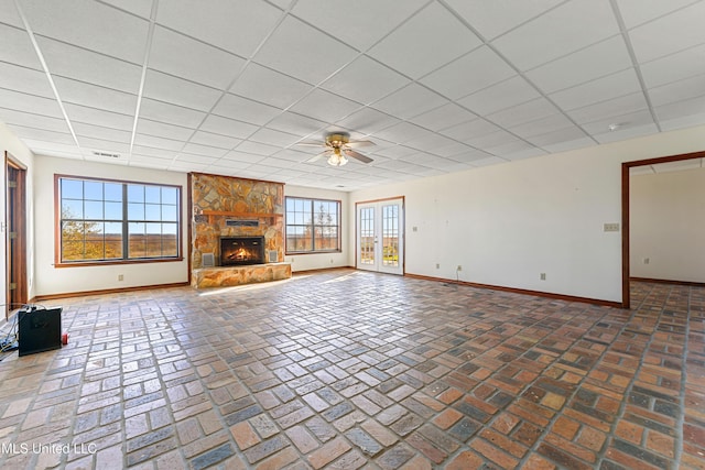 unfurnished living room featuring a fireplace, ceiling fan, and a drop ceiling