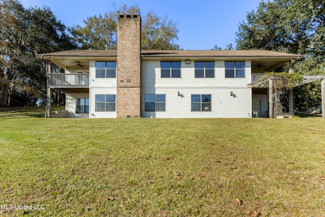 rear view of property with a lawn, ceiling fan, and a balcony