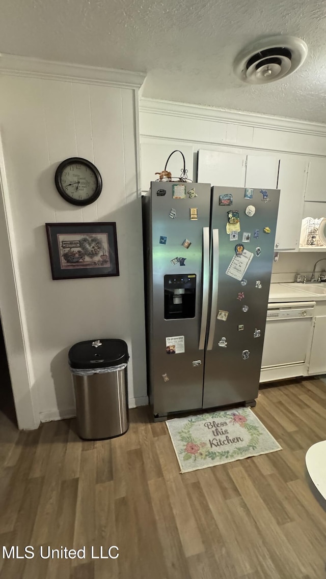 211 Boyd St, Ridgeland, MS 39157 - detailed view of stainless steel fridge with ice dispenser, dishwasher, white cabinetry, wood finished floors, and a textured ceiling