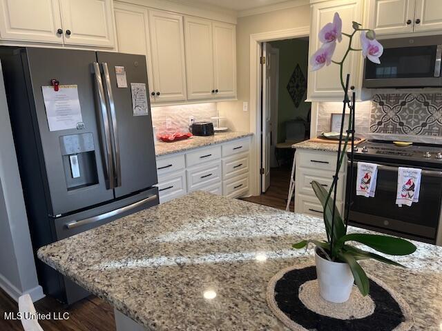 715 Sumner Ave, Greenwood, MS 38930 - kitchen featuring stainless steel appliances, white cabinets, light stone counters, dark wood finished floors, and decorative backsplash