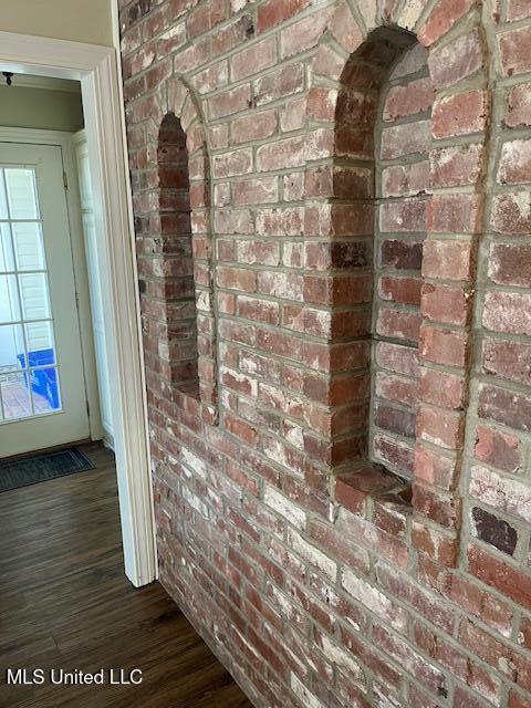 hall featuring dark wood-type flooring and brick wall